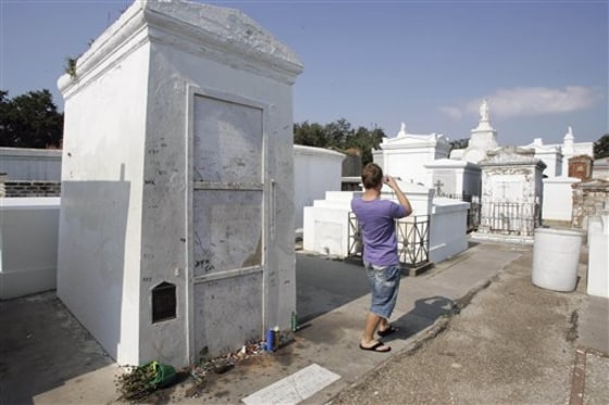 This Sept. 29, 2008, file photo shows a visitor as he takes a photograph of St. Louis Cemetery No. 1 with his back to what is believed to be the tomb of famous Voodoo priestess Marie Laveau, left, on the edge of the French Quarter in New Orleans.